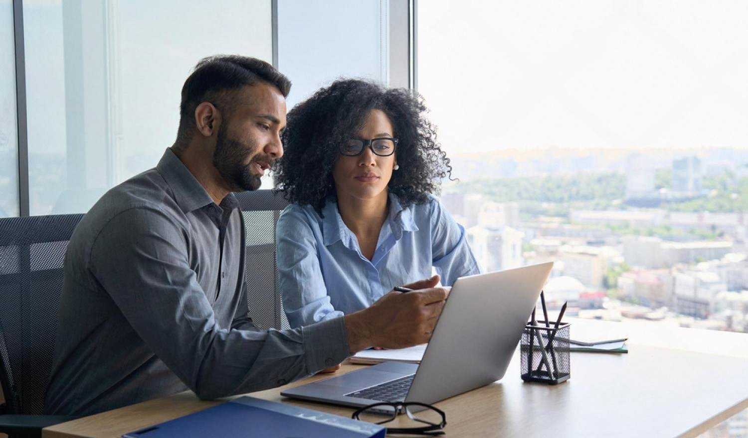 Two business professionals analysing a target company on a laptop in a Dubai office